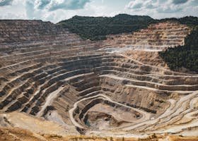 Aerial view of a large open-pit mine with terraced excavation during summer.